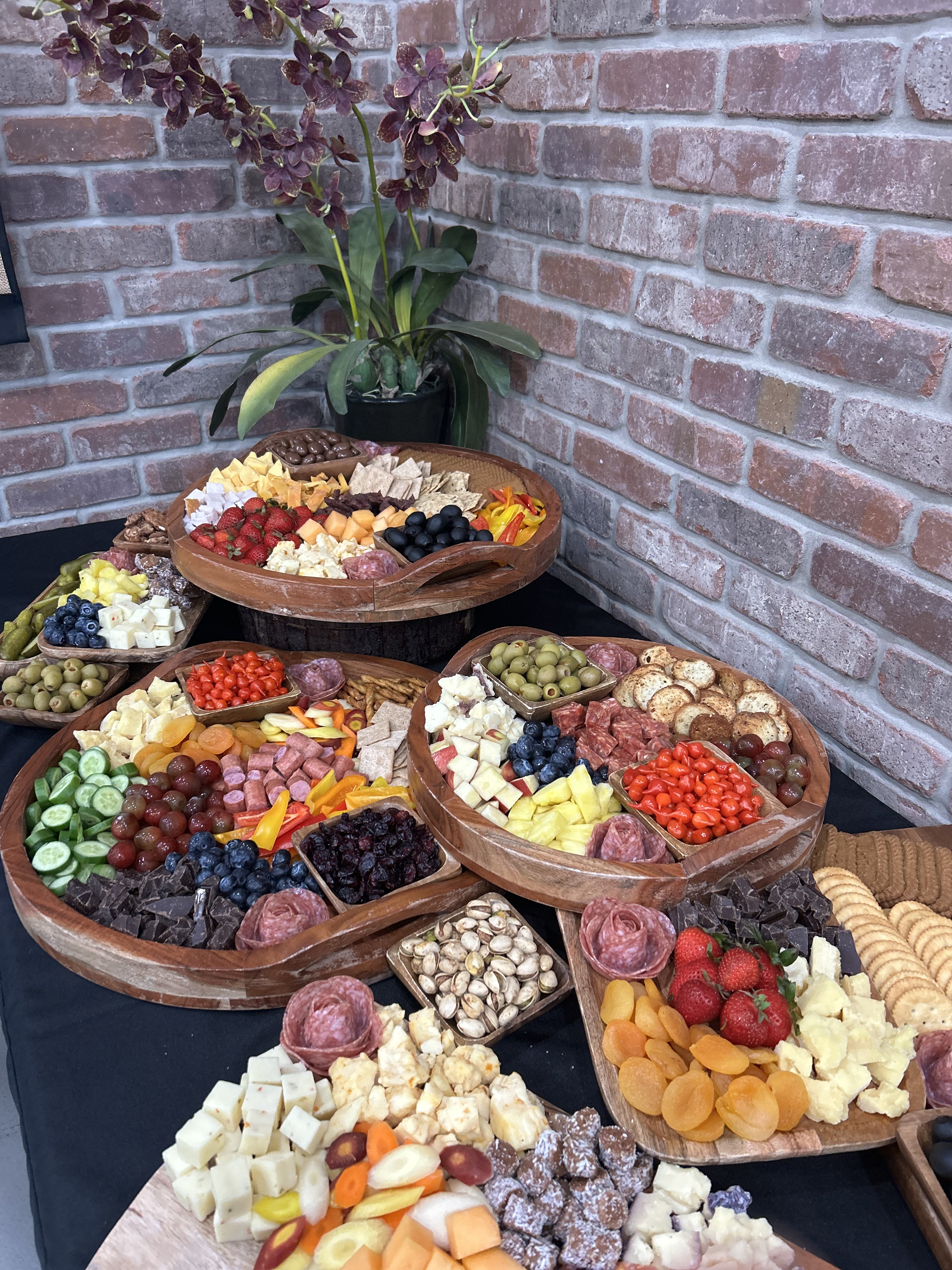 Tiered wooden charcuterie trays layered with fruit, cheese, and cured meats