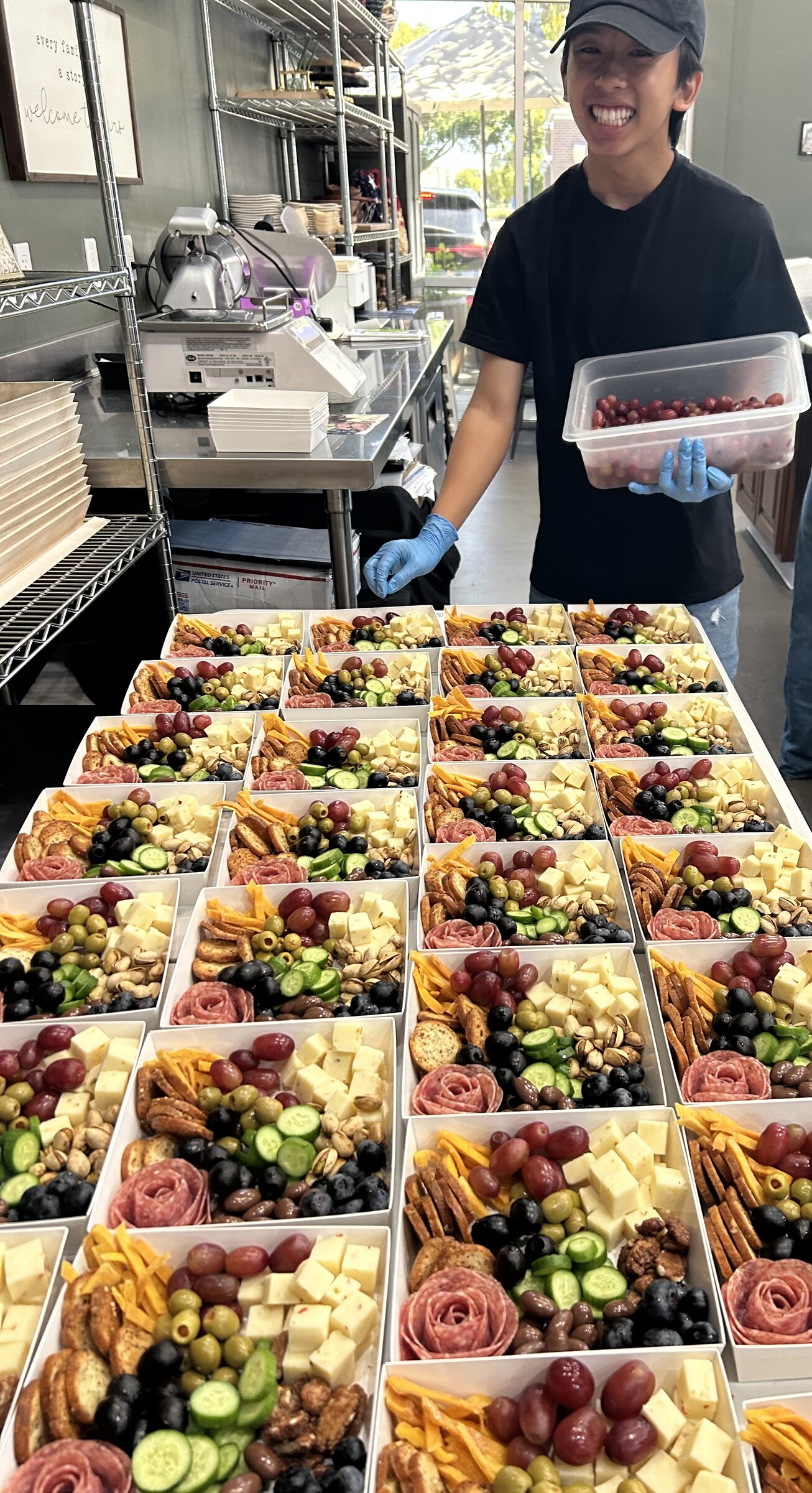 CharQterie team member preparing rows of individual catering boxes